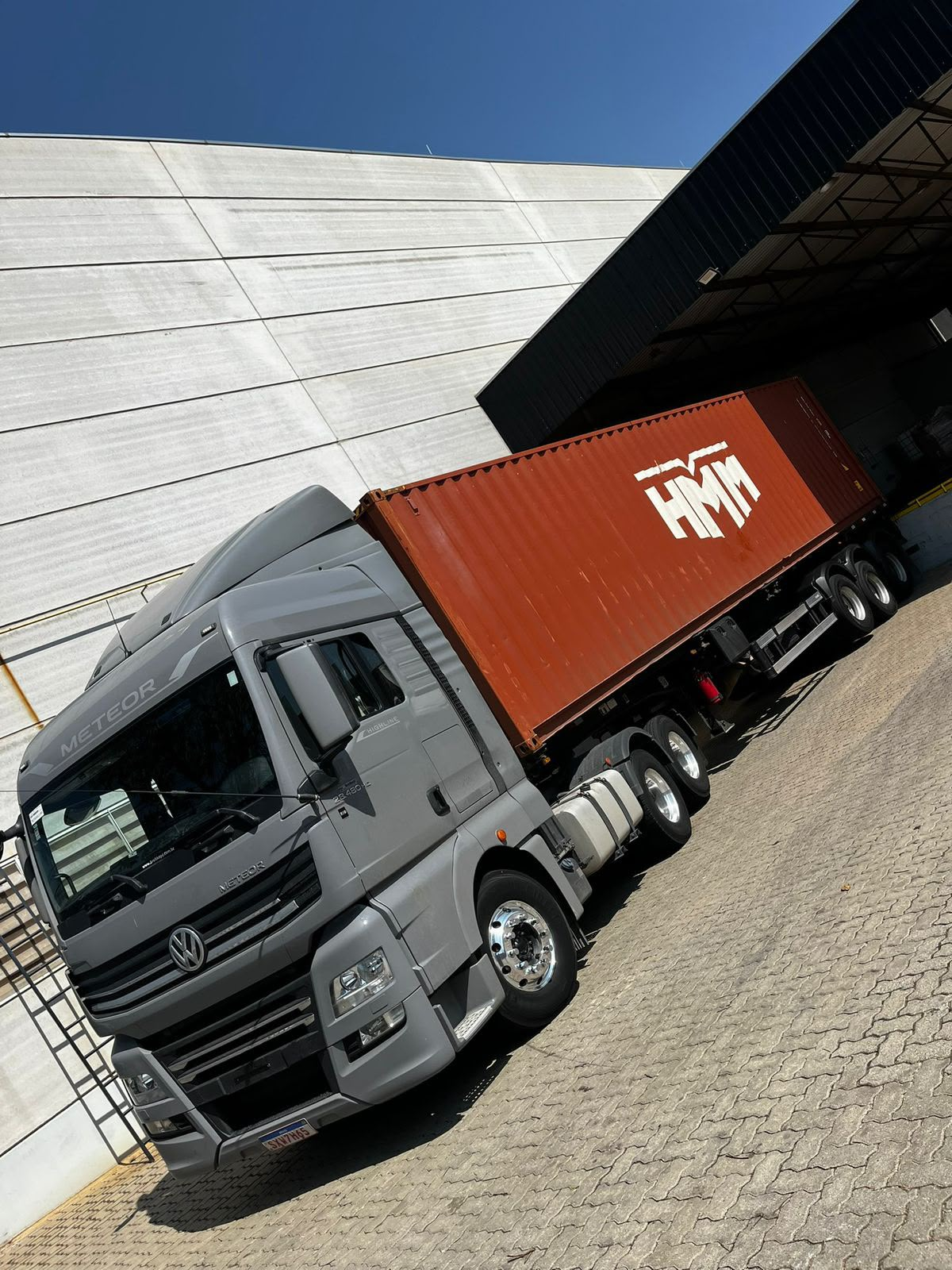 Caminhão cinza da MRS Transportes com container em pátio logístico